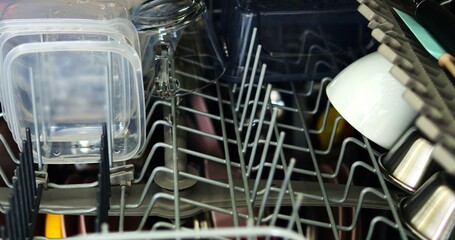 Clean dishware in steel drawer of dishwasher equipment in kitchen closeup. Machine for effective kitchen items washing at home. Hygiene improvement