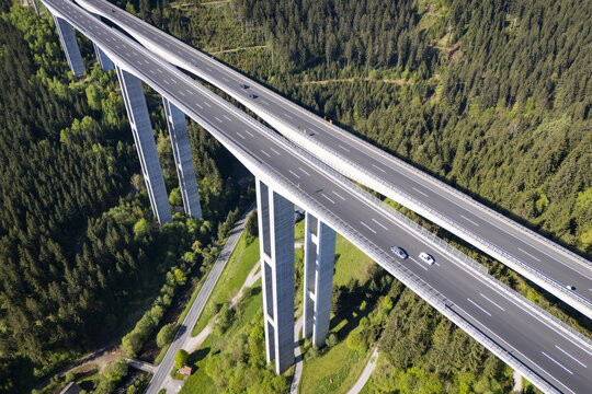 Aerial view of the towering Lavanttal bridge piercing through verdant forests, a symphony of concrete and nature's green embrace, Wolfsberg, Carinthia, Austria.