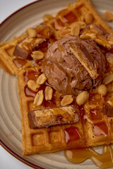 Decadent Waffle Delight with Chocolate Ice Cream, Drizzled with Syrup and Topped with Crunchy Peanuts and Chocolate Bars for an Irresistible Treat