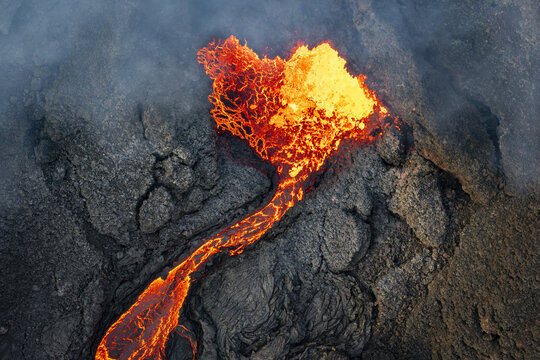 Aerial view of fiery orange lava snaking through the dark, textured landscape, a stark contrast of destruction and raw power, Grindavik, Grindav&Atilde;&shy;kurb&Atilde;&brvbar;r, Iceland.