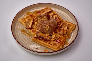 Deliciously Indulgent Waffles Topped with Creamy Chocolate Ice Cream, Crunchy Peanuts, and Drizzled with Rich Caramel Sauce for a Sweet Treat