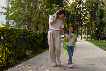 Obraz premium Mother and daughter walking together on a sunny day in the park