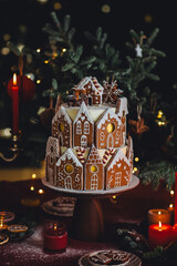 Beautiful traditional homemade gingerbread house. Celebration of Christmas and Happy new year at home. Festive mood, cozy atmosphere, red candles, fir tree branches. Elegant decor