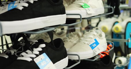 Sports store contains special shoes with price tags to buy branded product. Clean modern sneakers stand on metal stands attracting attention of customers
