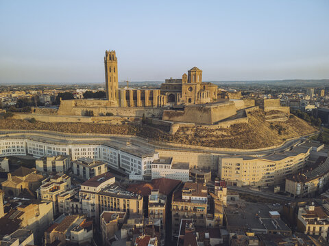 Aerial view of the Seu Vella cathedral perched atop a hill, casting a golden glow over the ancient city, Lleida, Lleida, Spain.