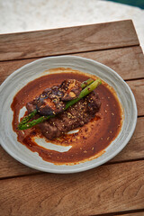 Deliciously Grilled Steak with Asparagus Garnish in Savory Sauce Served on a Rustic Wooden Table, Perfect for Gourmet Dining Experience