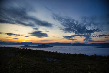 A summer night in a Norwegian fjord covered in fog