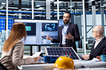 Photovoltaics factory executives planning strategic investment decisions, going over data. Investor and solar panels factory management team standing together discussing business data