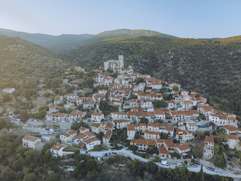 Aerial view of a cluster of red-roofed houses nestled in the rolling hills, crowned by a medieval church, Eus, Pyr&Atilde;&copy;n&Atilde;&copy;es-Orientales, France.