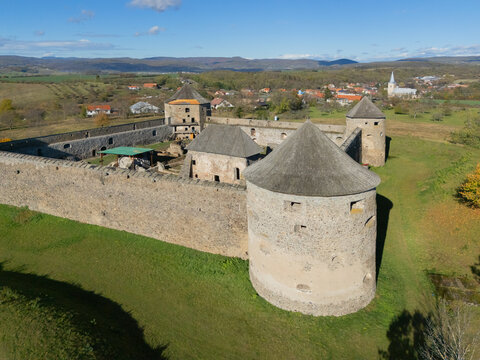 Aerial view of a medieval castle with cylindrical towers amidst a green landscape, under a clear blue sky, Bzov&Atilde;&shy;k, Krupina, Slovakia.