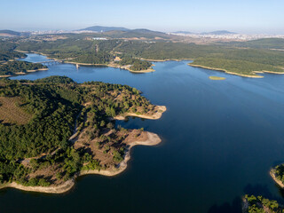 Aerial view of Ömerli Dam with vivid blue waters, lush green forests, and curving shorelines under...