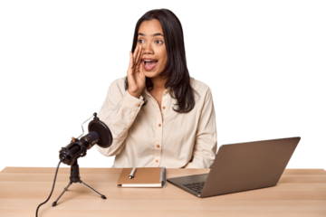 Woman records podcast with laptop shouting and holding palm near opened mouth.