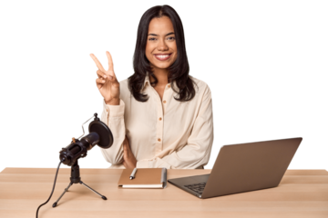 Woman records podcast with laptop showing number two with fingers.