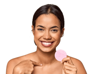 Woman holds facial sponge in studio person pointing by hand to a shirt copy space, proud and confident