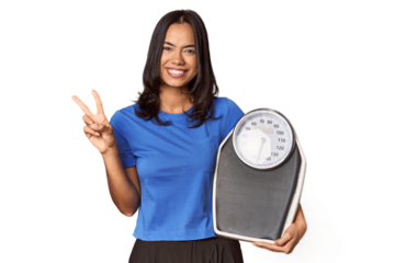Filipino woman with scale in studio showing number two with fingers.
