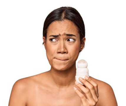 Filipino woman holds deodorant in studio confused, feels doubtful and unsure.