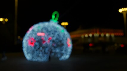Illuminated ball on ground during night. A view of big festive bal in garlands in the city square during night time. A concept of festive time during New Year holidays