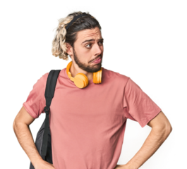 Young student with backpack and headphones confused, feels doubtful and unsure.