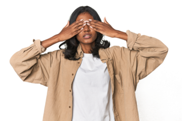 Portrait of a young Indian woman afraid covering eyes with hands.