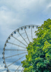 Fototapeta premium Sky Wheel with carriages viewed through trees on a cloudy day
