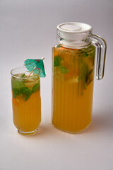 Refreshing Citrus Beverage Served in a Pitcher and Glass with Mint Leaves and Colorful Umbrella for a Vibrant Summer Experience