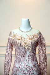 An elegant long-sleeved wedding gown in soft pink lace, adorned with intricate floral embroidery...