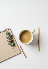 A minimalist arrangement of a notebook, coffee, and eucalyptus