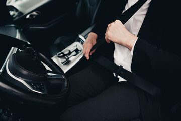 Professional driver fastening seatbelt inside stylish luxury automobile for safety and comfort...