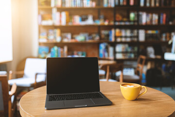 Workplace in cafe. Laptop computer with black blank screen and mug of coffee on wooden table. Notebook screen with copy space for your content. Mockup, empty space