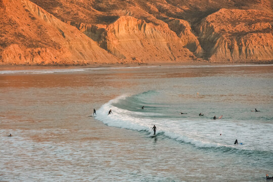 Waves breaking and surfers surfing in Imsouane, Morocco