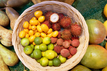 Colorful basket of exotic fruits including rambutan, lychee, and kumquat on a vibrant market display