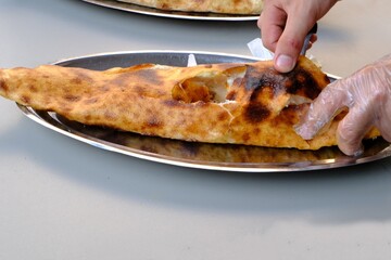 A chef pours butter into a traditional Turkish culinary delight: ground meat pide. Buttered ground meat pide is accompanied by buttermilk in a copper mug. Pastries. Food industry. Ramadan, iftar.
