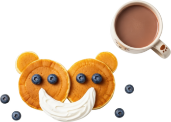 Two round pancakes decorated as a bear face with blueberries and whipped cream next to a mug of hot chocolate transparent background