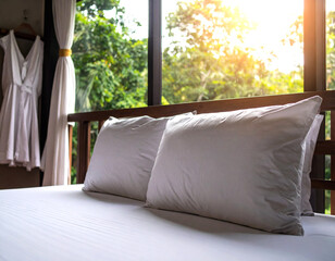 A bed with two white pillows and a white sheet