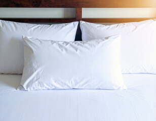 A white pillow sits on a bed with a white sheet