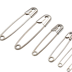 A group of shiny metal safety pins of varying sizes arranged diagonally on a black background isolated on transparent background