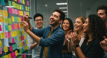 Happy creative team celebrating success during a brainstorming session with sticky notes in a modern office.
