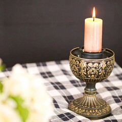 Decorative candle in ornate holder on checkered tablecloth