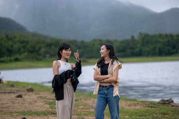 Two women standing by a lake, one pointing at something