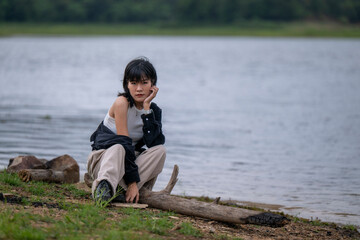 A woman sits on a log by a body of water