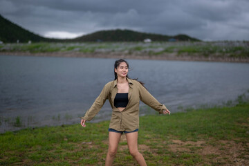Obraz premium A woman is standing in a grassy field near a body of water