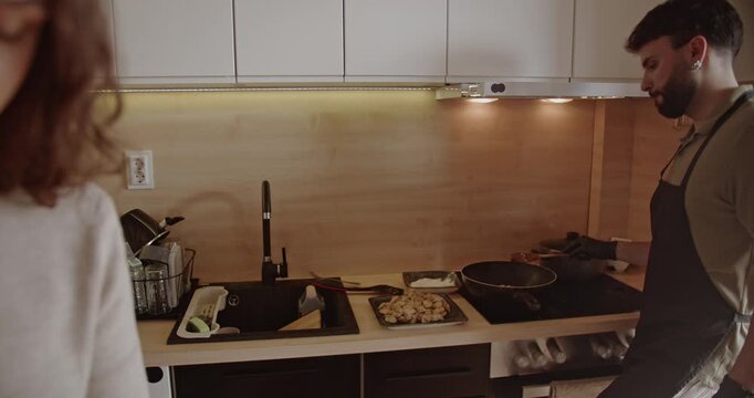 A young couple enjoys cooking and spending time together in their modern kitchen. They prepare a meal and share a moment of love and happiness.