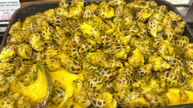 shells in curry sauce close up shot of a ladle spoon mixing a a meaty dish on a large saucer pan, slow motion