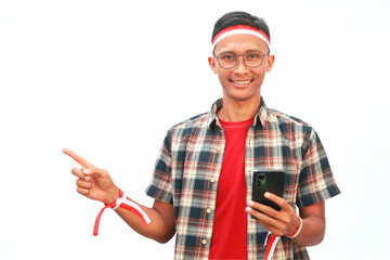 An Asian man wearing a red and white ribbon and holding a cell phone with his finger pointing up