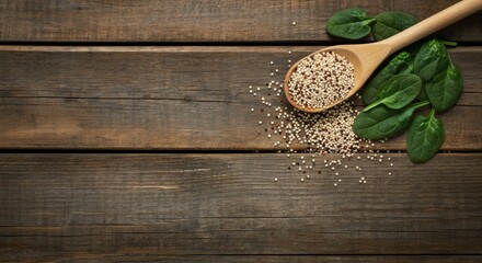 Wooden spoon filled with quinoa and fresh spinach leaves on rustic wooden table background