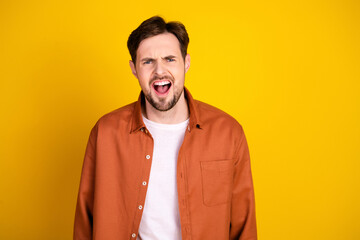 Obraz premium Stylish young man in a casual outfit smiles brightly against a vibrant yellow background expressing joy and fun.