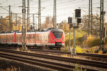 Speed blur on a German S‑Bahn trainset painted red speeds pass near a suburban station in autumn, demonstrating regional commuter rail transport and dense electrified network and suburban railway.