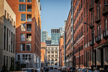 Brick apartment blocks (Condos) leading to glass office towers in downtown Montreal, Quebec, Canada showcasing the blend of heritage facades with modern corporate growth in Canada.