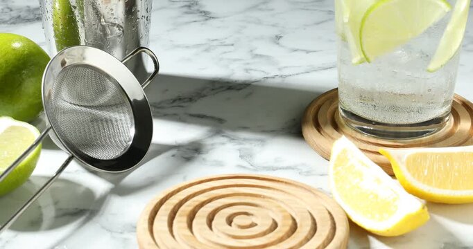Woman taking glass of refreshing cocktail with lemon at white marble table, closeup