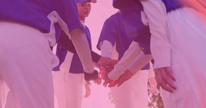 Stepping into circle six athletes in blue jerseys stacking hands and raising fists pregame on field